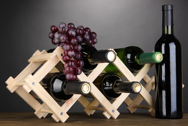 Bottles of wine placed on wooden stand on grey background