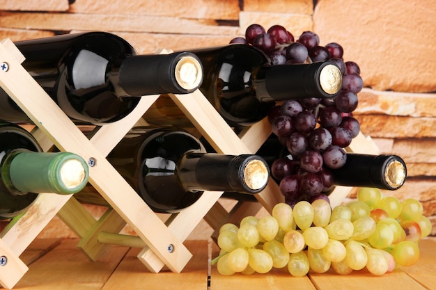 Bottles of wine placed on wooden stand on stone wall background