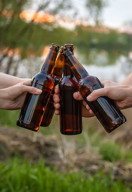 Bottles with beer in the hands of young people in nature