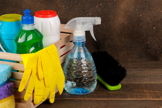 Bottles with cleansers and detergents in a box on a brown background. cleaning. cleaning products.