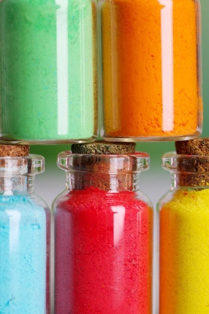 Bottles with colorful dry pigments on wooden background