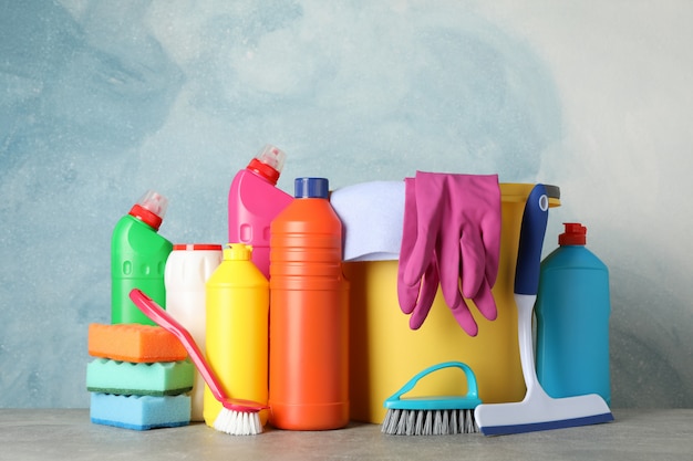 Photo bottles with detergent and cleaning supplies on blue background, space for text