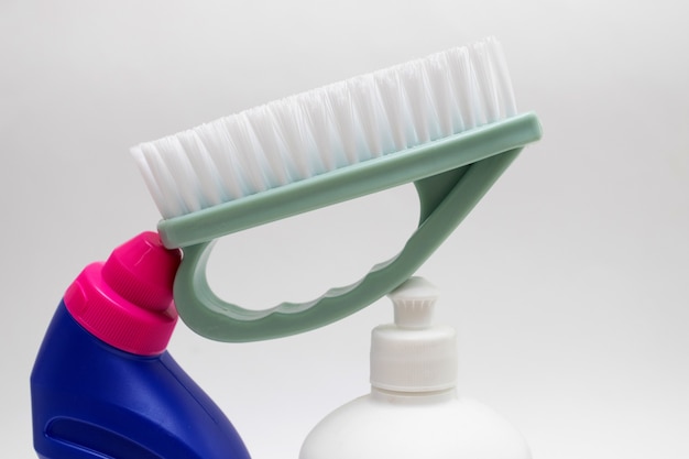 Bottles with detergent and Washing brush on white background