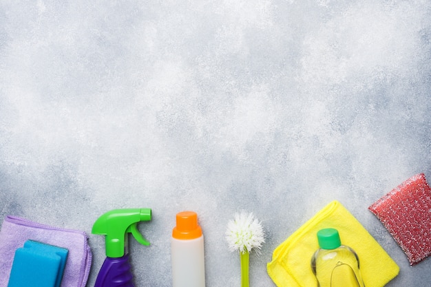 Bottles with detergents, brushes and sponges on concrete background. 