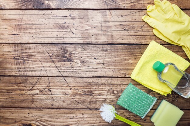 Bottles with detergents, brushes and sponges on wooden background. 