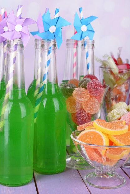 Foto bottiglie di bevande e dolci sul tavolo su uno sfondo luminoso