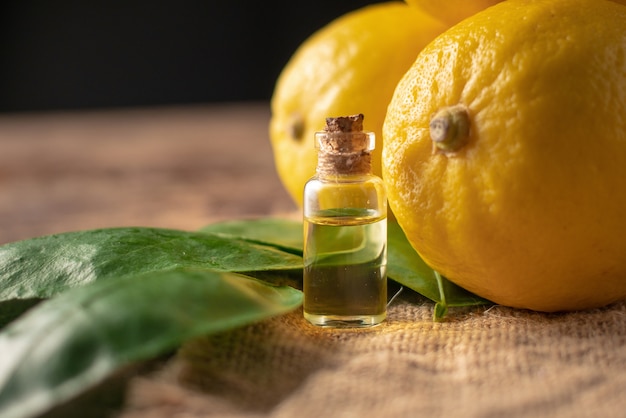 Photo bottles with essential oil of lemon peel and leaf on wooden table