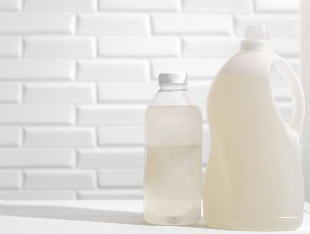 Bottles with laundry detergent and fabric conditioner on white
table unbranded cleaning products for housekeeping cleaning liquid
products for kitchen chores