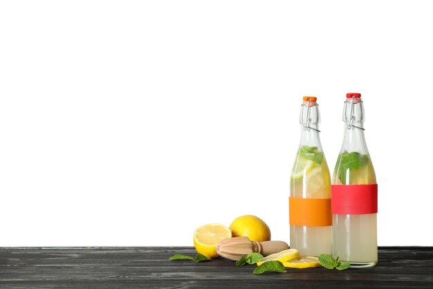 Photo bottles with natural lemonade on table against white background