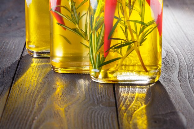 Bottles with oil, herbs and spices at wood table on black