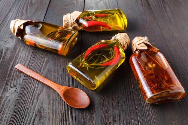 Bottles with oil, herbs and spices at wood table on black