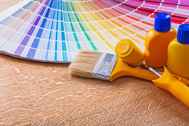 Bottles with paint paintbrush and roller color palette on wooden board