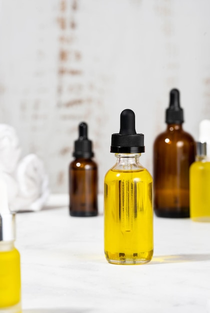 Bottles with serum oils and towel on the cosmetic table in the bathroom a set of organic cosmetics in glass vials with dropper for skin and hair care concept of self care and spa foreground focus