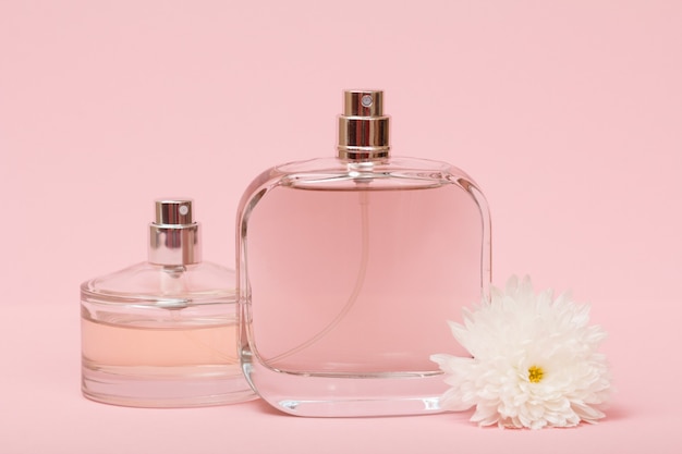 Bottles with women perfume and flower bud in a pink background. Women products.