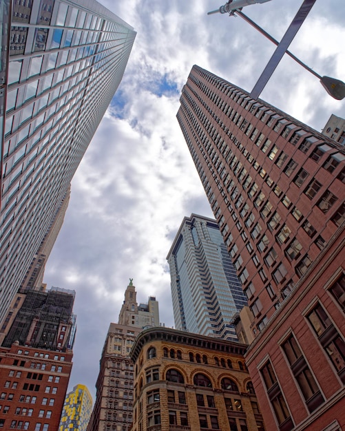 Bottom up Street view on Financial District of Lower Manhattan, New York City, NYC, USA. Skyscrapers tall glass buildings United States of America. Blue sky on background. Empty place for copy space.