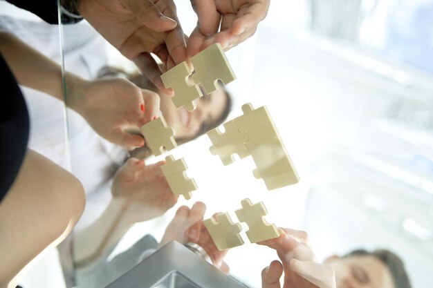 Bottom view business team folding puzzle pieces