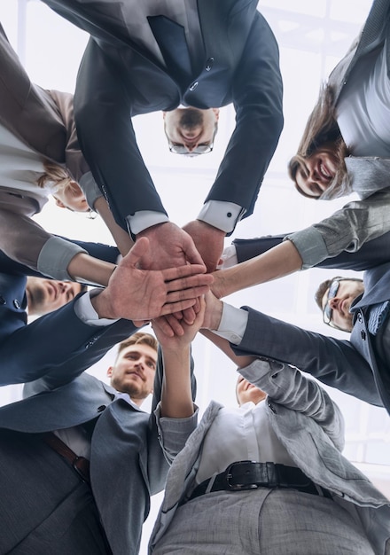 Bottom view business team showing unity with their hands togetherthe concept of teamwork