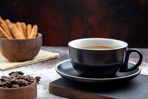 bottom view cup of coffee on wood board bowls with cinnamon sticks and roasted coffee beans on table