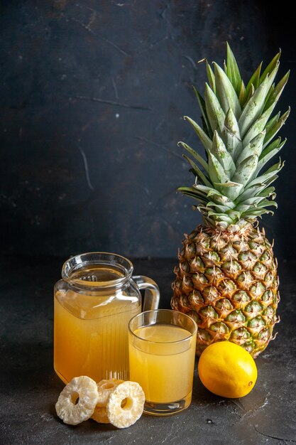 bottom view fresh pineapple juice in glass and carafe lemon on dark background