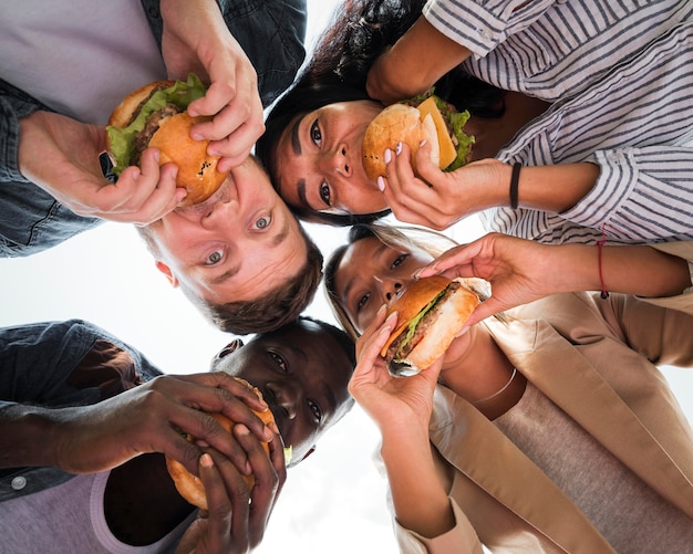 Photo bottom view friends eating burgers