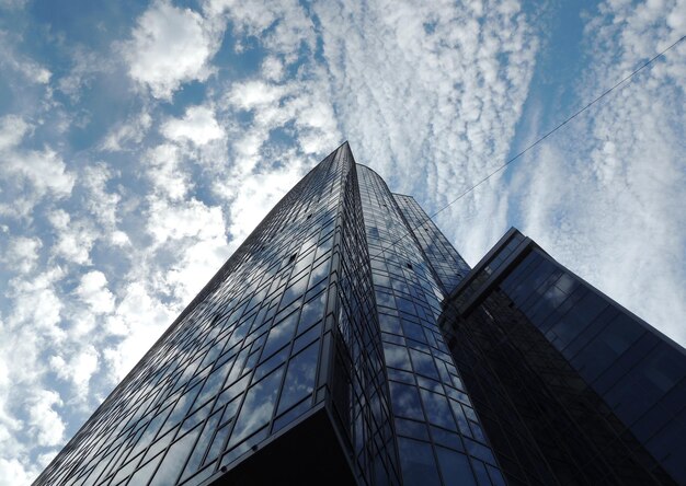 Bottom view of the glass office building with clouds reflection in windows