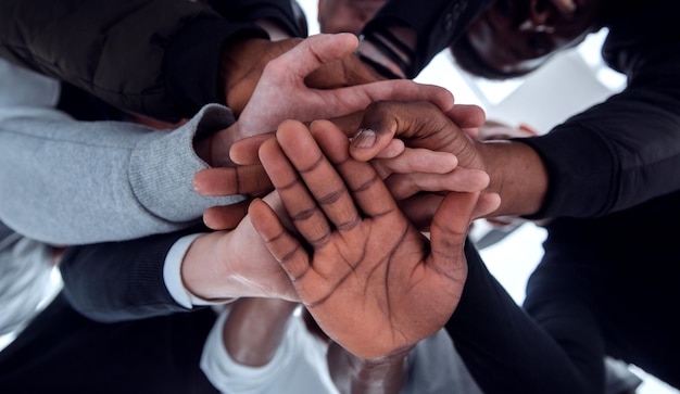 Bottom view a group of diverse young people joining their hands together