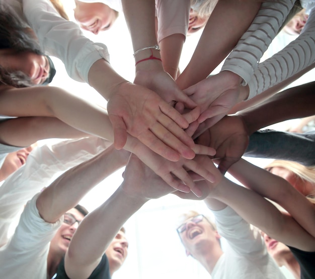 Bottom view group of young people joining their palms together