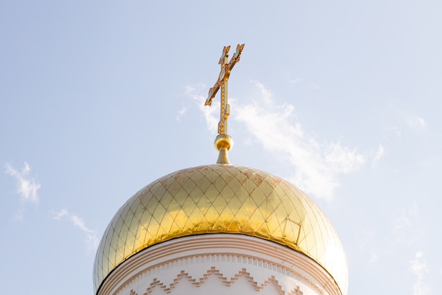 Bottom view of shiny sunlit christian church dome with cross on top