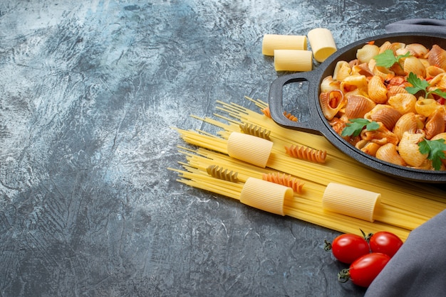 bottom view tasty pasta in frying pan spaghetti rigatoni spirals cherry tomatoes on grey background free space