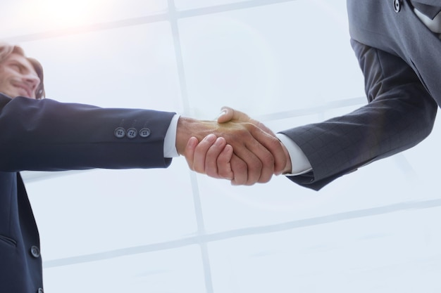 Bottom view of two men shaking hands while standing