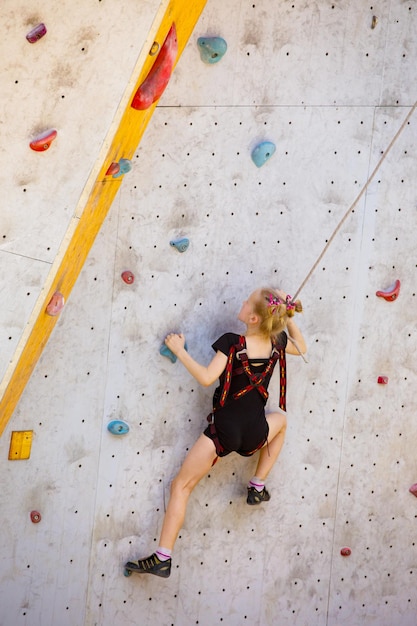 Boulderen, klein meisje dat tegen de muur klimt