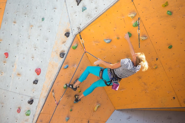 Bouldering, girl climbing up the wall