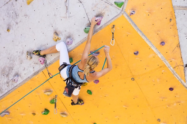 Bouldering, girl climbing up the wall