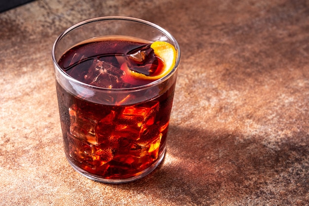 Boulevardier cocktail and orange zest on wooden table