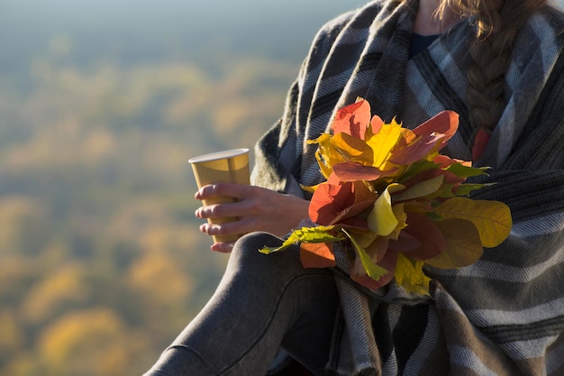 Photo bouquet of autumn leaves and paper cup in a female hand close up