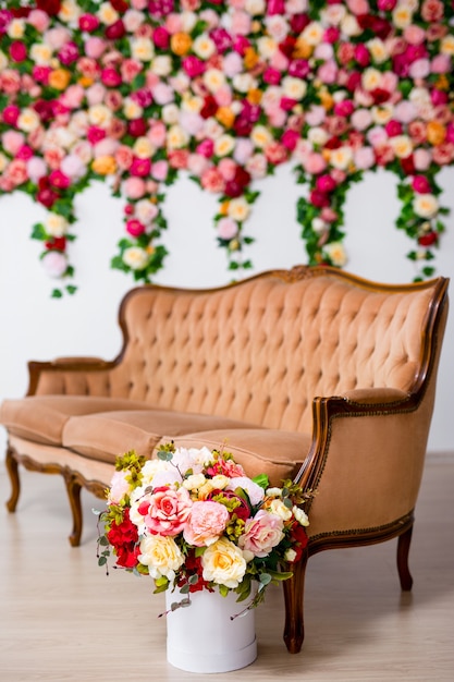 Bouquet of beautiful flowers in box and vintage sofa over colorful summer flowers background