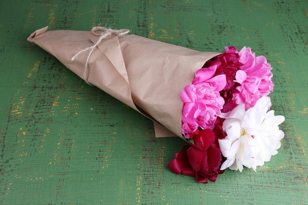 Photo bouquet of beautiful peonies on wooden background