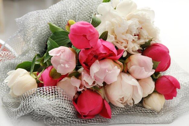 Photo bouquet of beautiful peony flowers on light table closeup