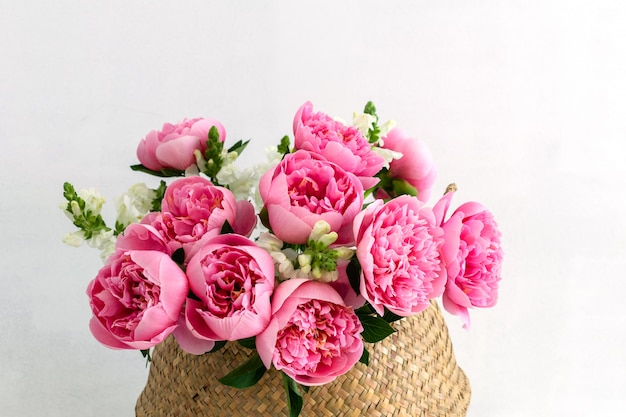 Bouquet of beautiful pink peonies in straw basket