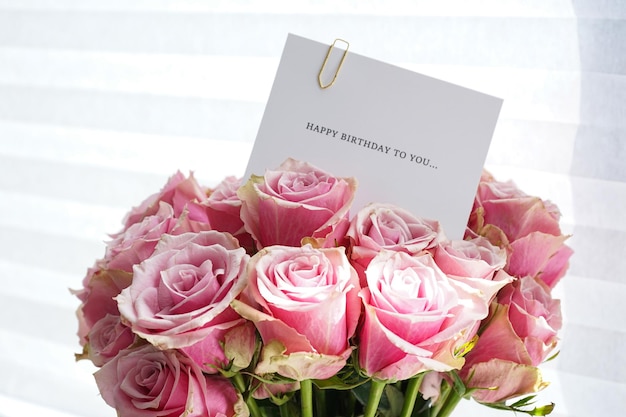 Bouquet of beautiful pink roses with a greeting card top view Closeup