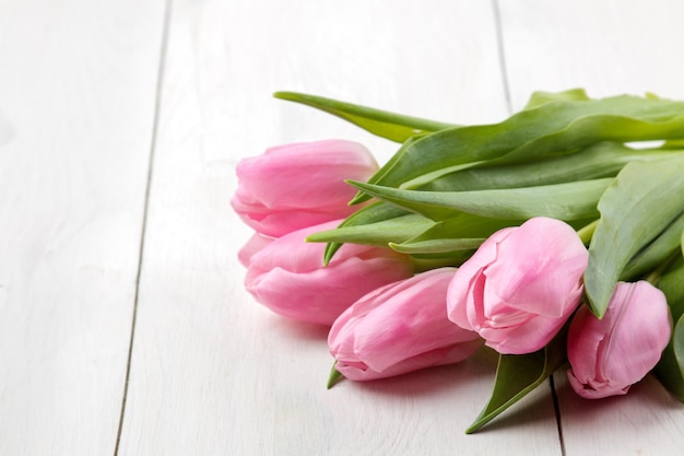 A bouquet of beautiful pink tulips flowers on a white wooden table Spring holidays closeup