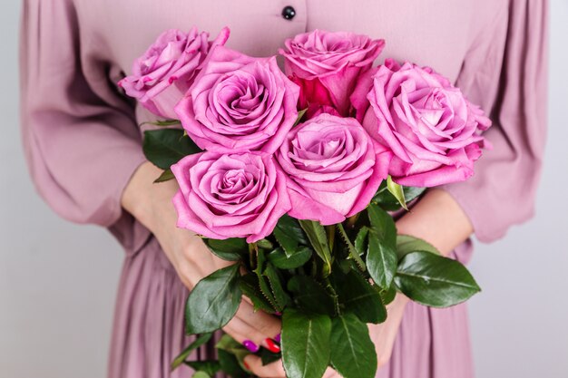 A bouquet of beautiful roses in the hands of a woman