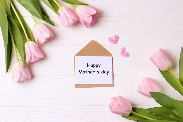 A bouquet of beautiful tulips and a card for text on a wooden background