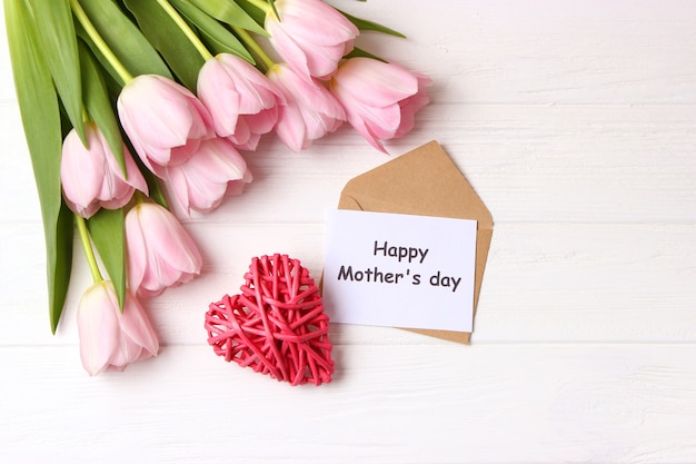 A bouquet of beautiful tulips and a card for text on a wooden background