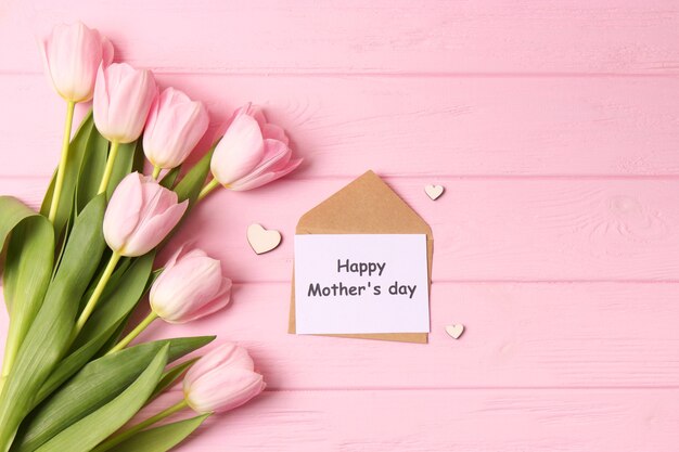 A bouquet of beautiful tulips and a card for text on a wooden background