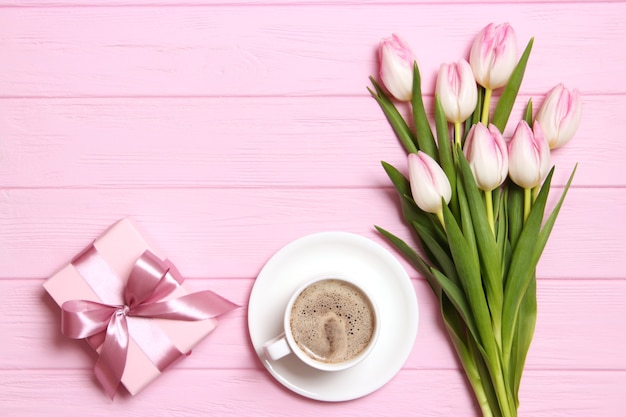 A bouquet of beautiful tulips and a gift on a wooden background top view