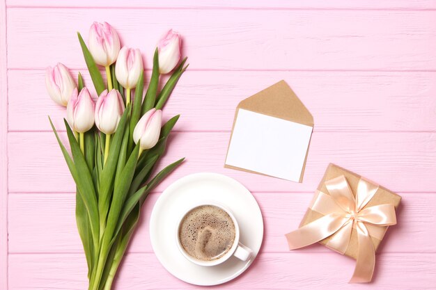 A bouquet of beautiful tulips and a gift on a wooden background top view