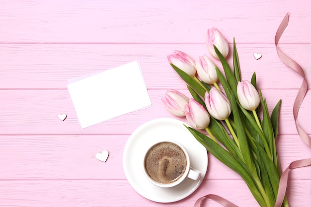 A bouquet of beautiful tulips and a gift on a wooden background top view