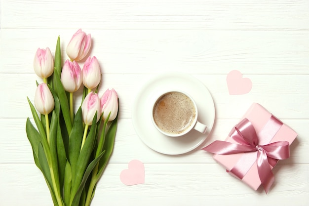 A bouquet of beautiful tulips and a gift on a wooden background top view