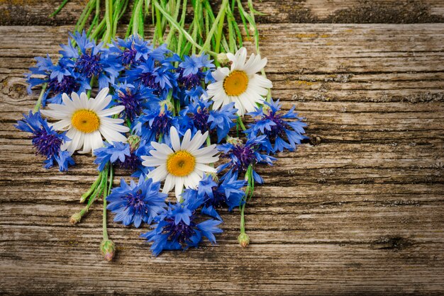 bouquet of blue cornflowers and daisies close-up on a wooden 